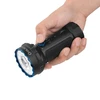 Hand holding a black and blue Olight Arkflex X9 flashlight, with thumb on control knob.