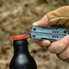 NexTool multi-tool bottle opener lifting a red metal cap off a black glass bottle outdoors