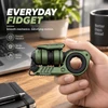 GoBiggeR green metal EDC fidget toy held in hand over office desk, featuring smooth rotation and tactile feedback.