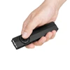Hand holding a compact black Olight flat EDC flashlight with thumb on the power switch, isolated on white background.