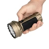 Hand holding a beige Olight Marauder Mini flashlight with black grip and map pattern.