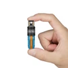 Hand holding a tiny Olight keychain flashlight in blue and orange racing stripe design against a white background