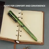 Green bolt action tactical pen with LED light and laser measuring 6.10 inches on an open leather notebook