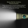 Green tactical flashlight with a rotary dial for stepless dimming control, emitting a bright white light beam.